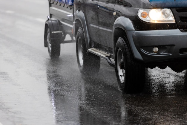 Schwarzes Offroad-Auto mit Hinterwagen hinten auf nasser Asphaltstraße an regnerischen Tagen