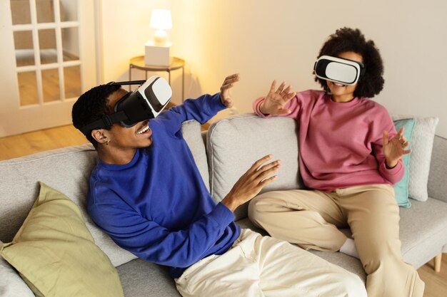 Schwarzes Paar mit VR-Brille taucht in die erweiterte Realität im Innenraum ein