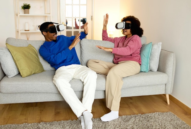 Schwarzes Paar trägt VR-Headsets und spielt zu Hause ein virtuelles Spiel