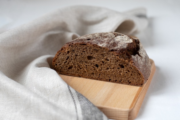 Schwarzes Roggenbrot auf einem Holzbrett schneiden