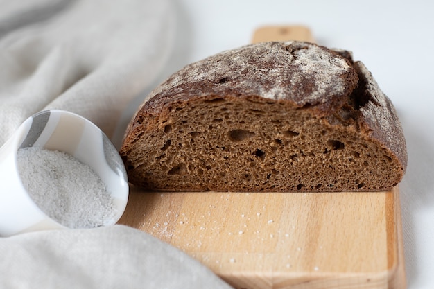 Schwarzes Roggenbrot mit Salz auf einem Holzbrett schneiden