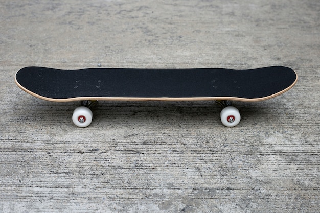 Schwarzes Skateboard auf Zementgrund. Speicherplatz kopieren