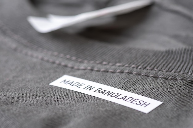 Foto schwarzes t-shirt mit der aufschrift „made in bangladesh“ in großaufnahme. herstellung von kleidung in südasien, preisgünstiges, zugängliches outfit für menschen