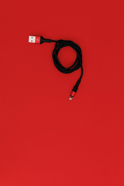 Schwarzes USB-Kabel auf rotem Hintergrund Thema Technologie