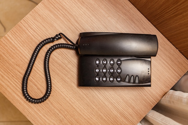 Schwarzes Vintage-Telefon auf einem braunen Tisch im Hotel.