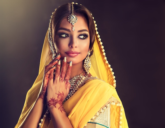 Schwarzhaarige indische junge Frau, angezogen in einem noblen Outfit Lehenga Choli Verschleierter Kopf prächtiges Make-up und nobler indischer Schmuck setzen indische Schönheit