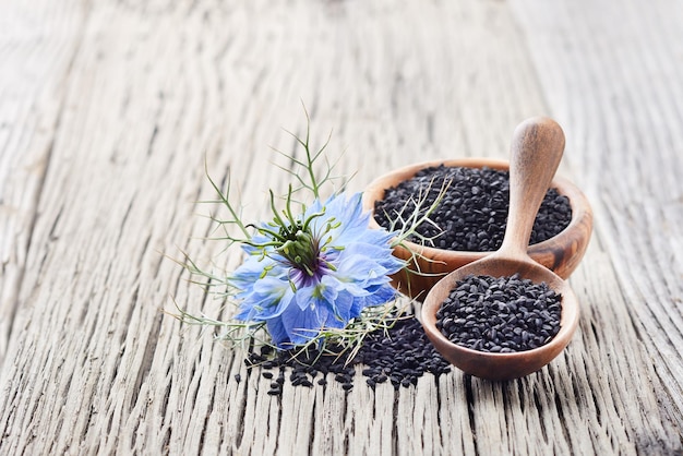 Foto schwarzkümmelsamen mit blüte auf einem holzbrett