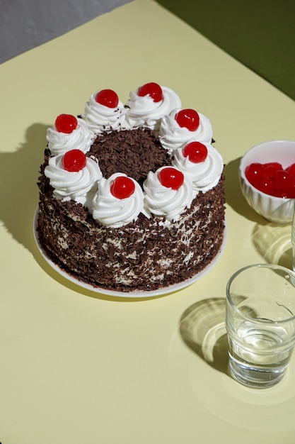 Schwarzwalder kirschtorte, bolo da floresta negra, luz forte, fundo da mesa sob a luz do sol, natureza morta moderna, sobremesa de cereja em fundo moderno