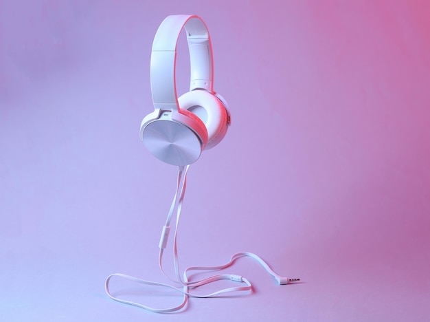 Schwebende Stereo-Kopfhörer mit weißem Kabel in rosa-blauem Neon-Gradientenlicht