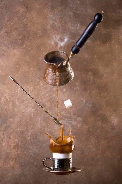Schwebender Kaffee und Türke auf braunem Hintergrund. Kaffeespritzer. türkischer Kaffee.