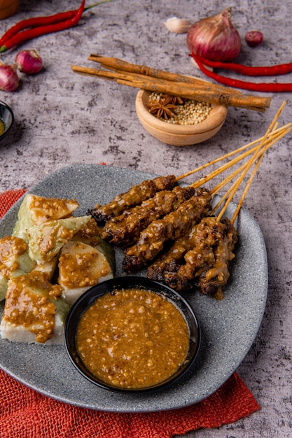 Schweine-Satay oder Sate Babi Schweine-Satay serviert mit einer Erdnusssauce und Scheiben von Lontong- oder Ketupat-Reiskuchen