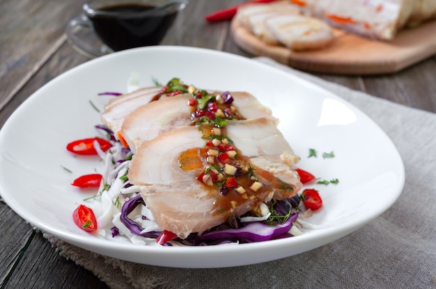 Schweinebauch mit Kohlsalat in einer weißen Schüssel auf einem hölzernen Hintergrund. Chinesische Küche.