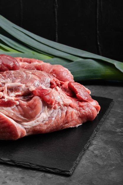 Schweinefilet, frisch Fleisch auf einer Schieferplatte auf grauem Hintergrund mit Gemüse. kopierraum, foto für lebensmittelgeschäfte.