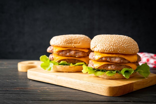 Schweinefleisch-Hamburger oder Schweinefleisch-Burger mit Käse auf Holzbrett