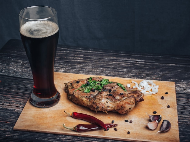 Schweinefleisch mit Knoblauch, Pfeffer, Zwiebeln und einem Glas dunklem Bier