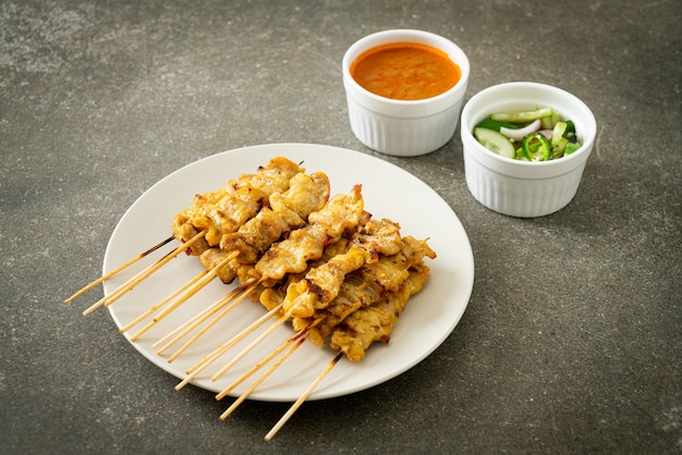 Schweinefleisch-Satay mit Erdnusssauce Gurkenscheiben und Zwiebeln in Essig - asiatische Küche