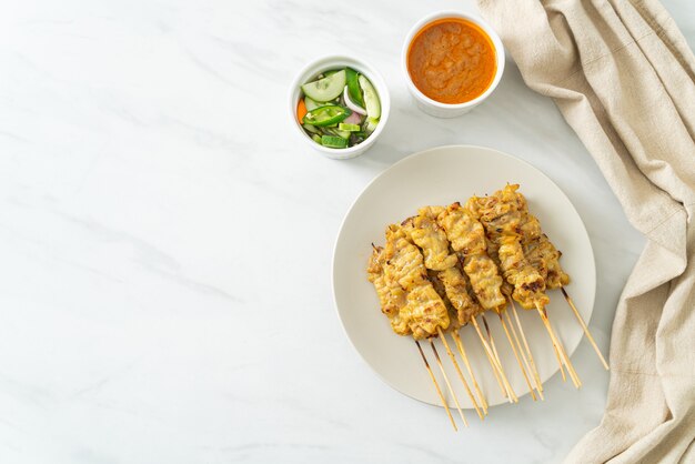 Schweinefleisch-Satay mit Erdnusssauce Gurkenscheiben und Zwiebeln in Essig - asiatische Küche