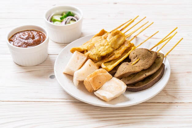 Schweinefleisch Satay mit Ihrer Erdnusssauce und Gurken, die Gurkenscheiben und Zwiebeln in Essig sind