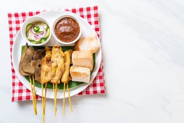 Schweinefleisch-Satay und Leber-Satay mit Brot-Erdnuss-Sauce und Gurken, Gurkenscheiben und Zwiebeln in Essig - asiatische Küche