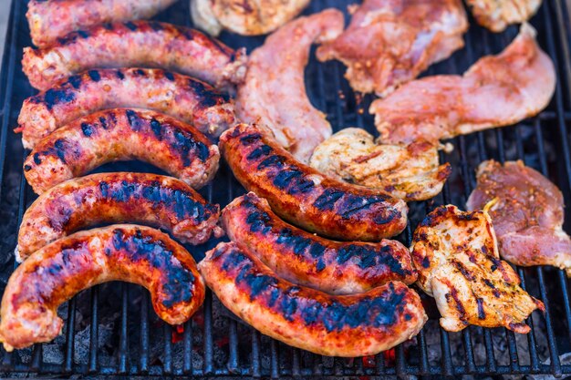 Foto schweinefleisch und würstchen grillt auf einem holzkohle-barbecue top-ansicht des leckeren barbecue-essen konzept essen auf dem grill und details des essens auf dem grill