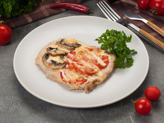 Schweinekotelett mit Pilzen und Tomaten, dekoriert mit Kräutern