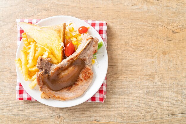 Schweinekotelettsteak mit Pommes und Minisalat auf weißem Teller