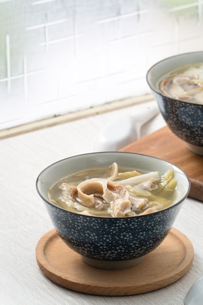 Schweinemagen-Schweineschlund mit eingelegtem Senfgrüngemüse. Taiwanesisches traditionelles Suppenessen in einer Schüssel neben dem Fenstertisch.