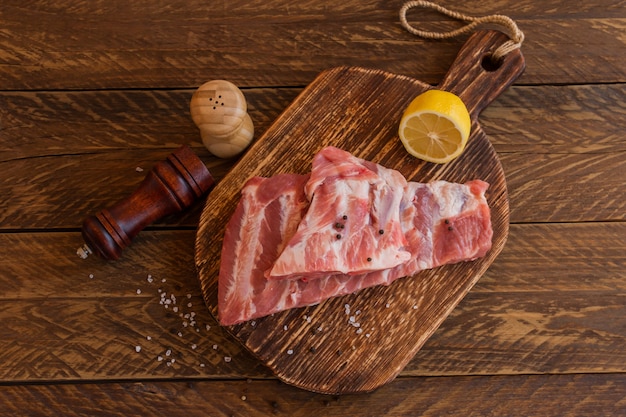 Schweinerippchen mit Gewürzen ungekocht auf Holzbrett. Rostiger Stil.