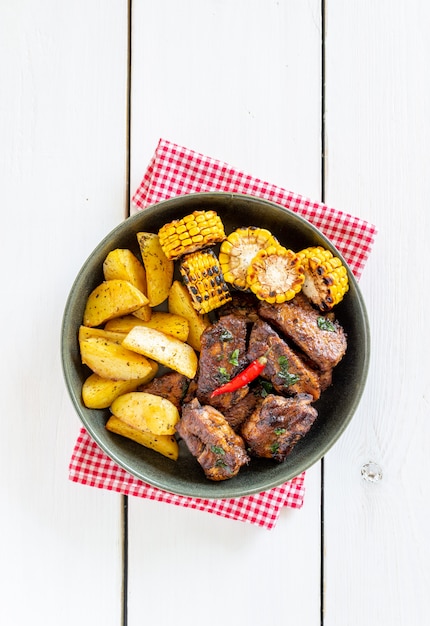 Schweinerippchen mit Kartoffeln auf einem Holztisch. Grill. Grill. Amerikanische Küche. Rezept.