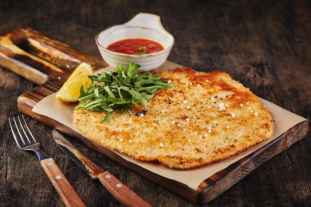 Schweineschnitzel mit Tomatensauce auf dunklem Holzhintergrund