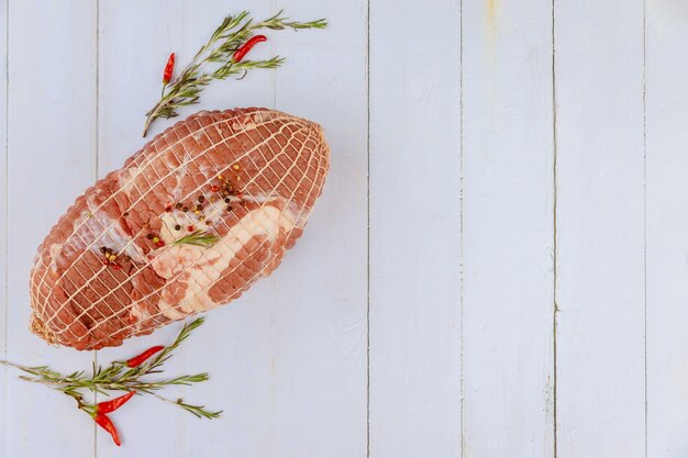 Schweineschulterbraten mit Gewürzen auf weißem Holztisch. Draufsicht