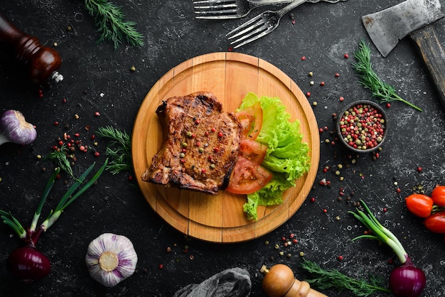 Schweinesteak am Knochen mit Gemüse auf dem Brett Grillmenü Draufsicht