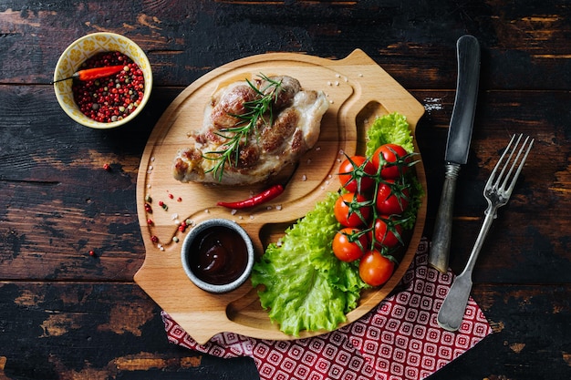 Schweinesteak auf einem Holzbrett mit Kirschtomaten und rustikalem Salatessen