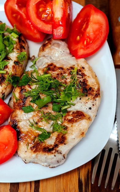 Schweinesteak mit Tomaten und frischen Kräutern.