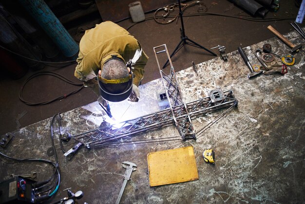 Schweißer schweißt Metalllayout eines Baukrans auf dem Eisentisch