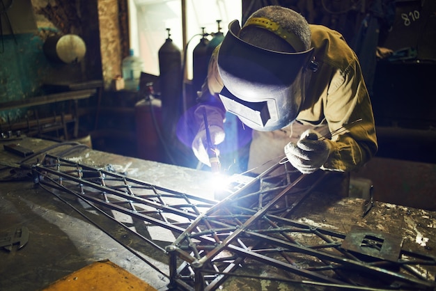 Schweißer schweißt Metalllayout eines Baukrans auf dem Eisentisch