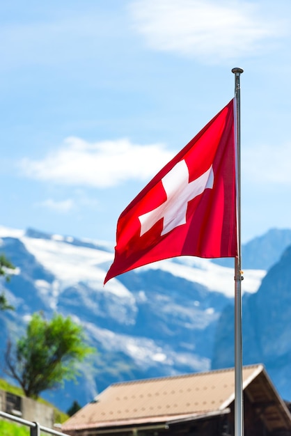 Schweizer Flagge gegen Alpenberge Vertikale Aufnahme mit selektivem Fokus