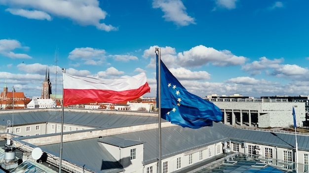 Schwenkende polnische Flagge und Flagge der Europäischen Union auf dem Gebäude