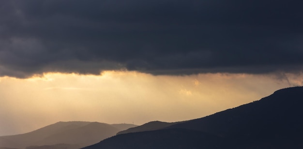 Schwere dunkle Wolken am Himmel über den Bergen bei Sonnenuntergang Cumulus dunkelgraue Wolkenlandschaft