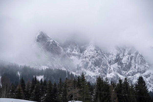 Schwere Schneewolken hängen über den schneebedeckten Bergen und Fichten