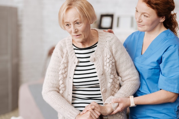 Foto schwere schritte. ältere empfindliche schwache frau mit einem besucher aus dem örtlichen krankenhaus, der ihr hilft und sich um ihre gesundheit kümmert