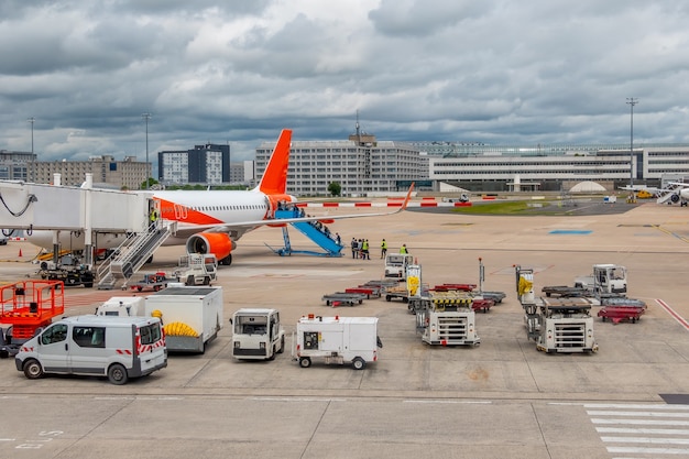 Schwere Wolken über dem Flugplatz. Viele Hilfsgeräte. Passagiere besteigen das Flugzeug entlang der Rampe