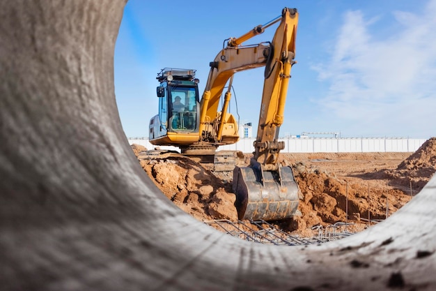 Schwerer Bagger auf der Baustelle Blick auf den Bagger durch das Eisenrohr Baumaschinen für Erdarbeiten Steinbruchbagger