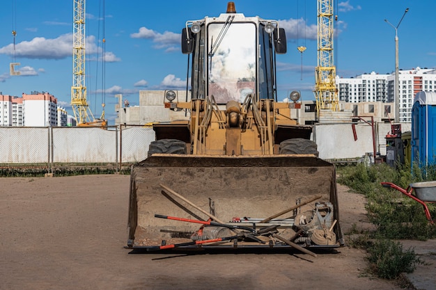 Schwerer Frontlader auf einer Baustelle mit einem Bauwerkzeug in der Schaufel. Ausrüstung für Erdarbeiten, Transport und Verladung von Schüttgütern - Erde, Sand, Schotter.