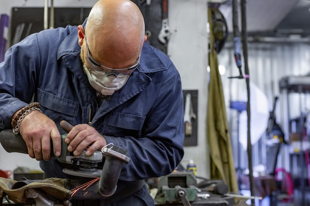 Schwerindustriearbeiter, der Stahl mit Winkelschleifer am Autoservice schneidet