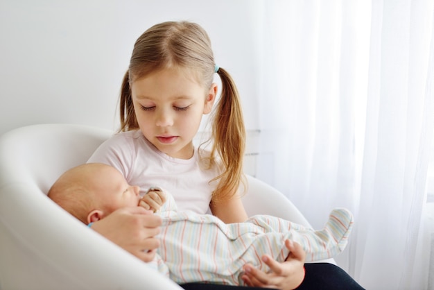 Schwester hält ihren neugeborenen Bruder zu Hause