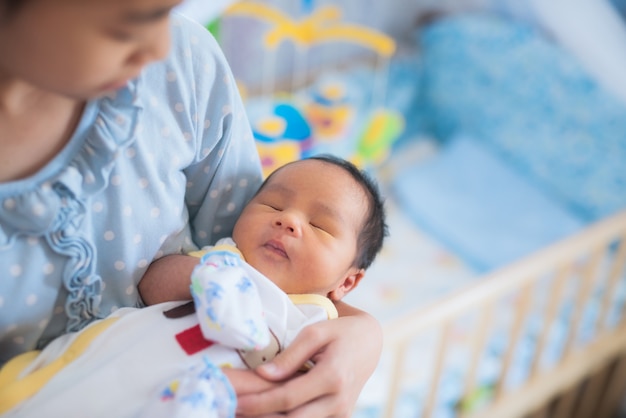 Schwester holt asiatischen neugeborenen Bruder zum Schlafen