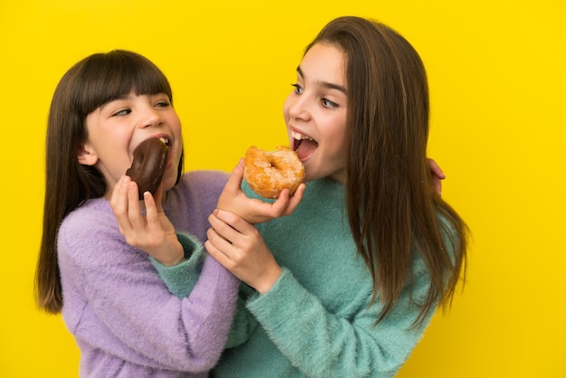 Schwestern, die einen Donut über isoliertem Hintergrund halten