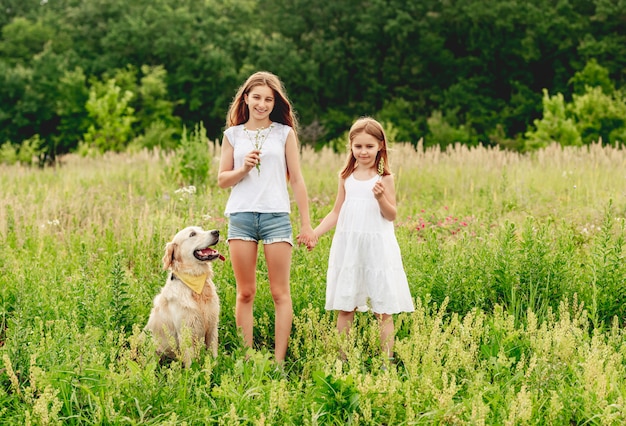 Schwestern mit Hund auf blühender Wiese