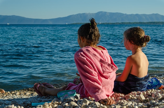 Schwestern sitzen nach dem Schwimmen am Meer